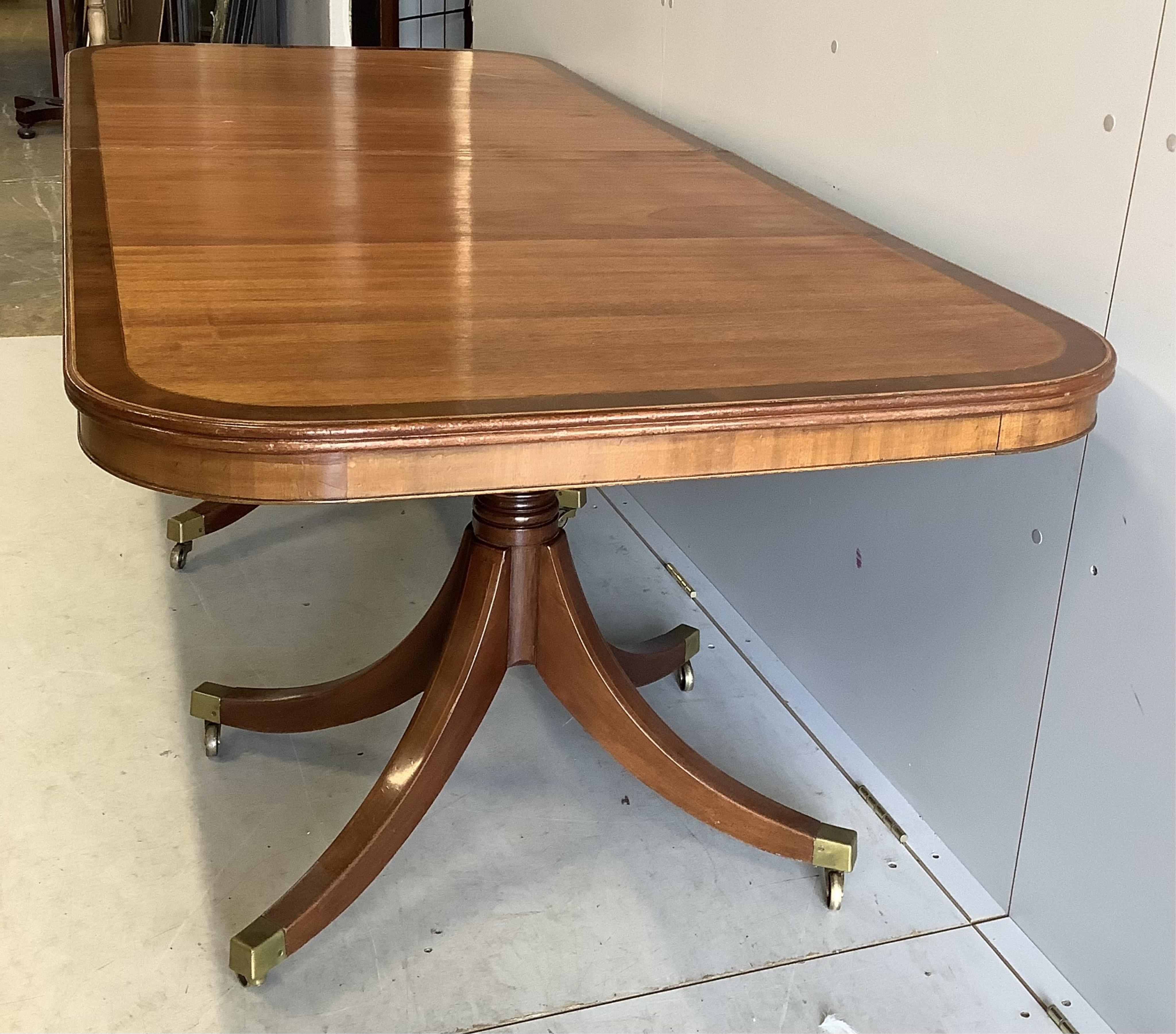 A set of ten Sheraton style mahogany dining chairs, two with arms together with a reproduction banded mahogany twin pillar extending dining table, 300cm extended, depth 91cm, height 72cm. Condition - fair to good